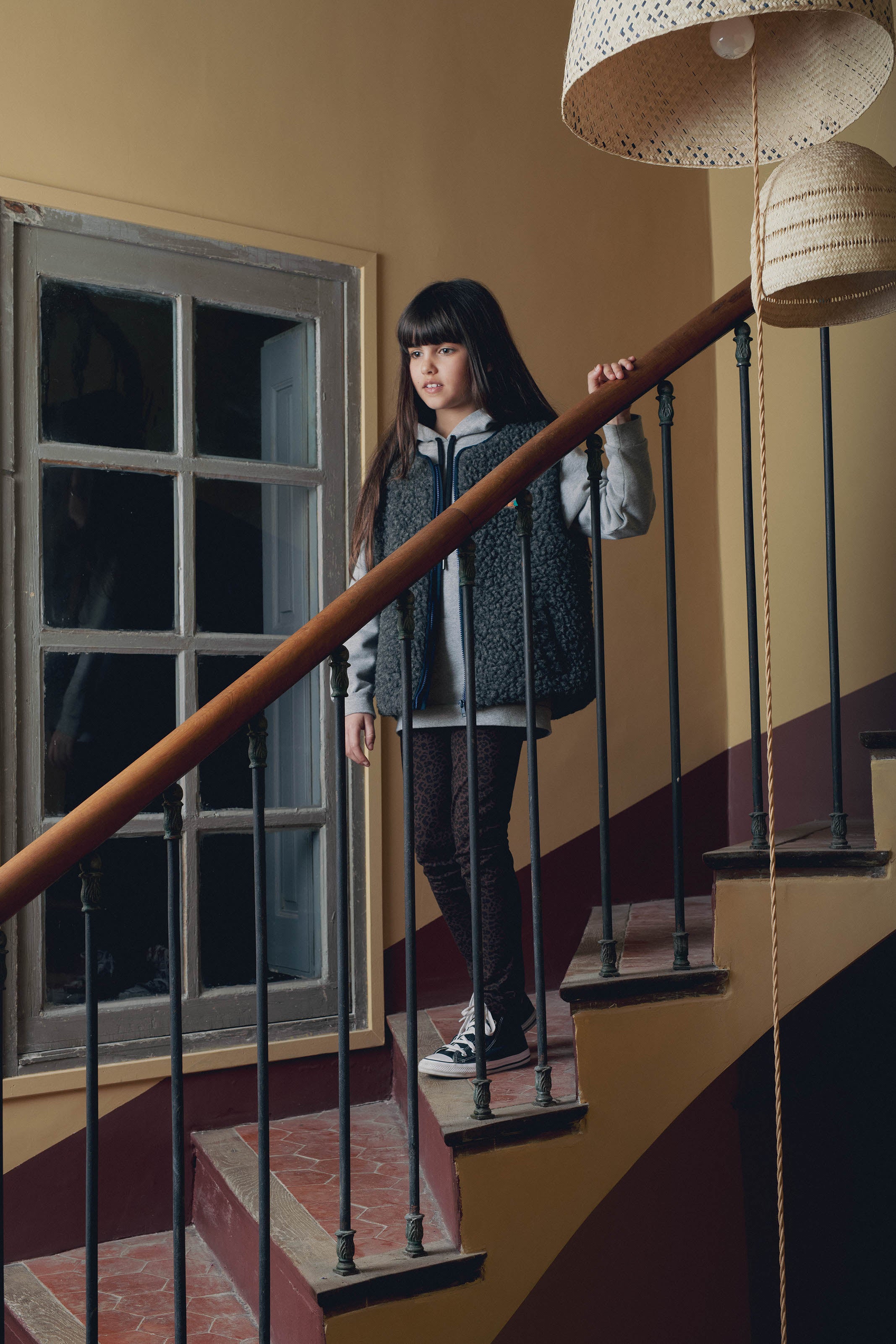 Portrait fille gilet moumoute gris legging dans escalier Marlot Paris