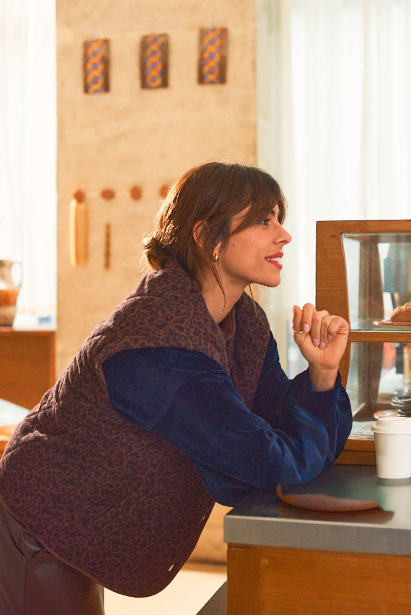 Portrait femme accoudée comptoir café portant gilet léopard brun Marlot Paris.