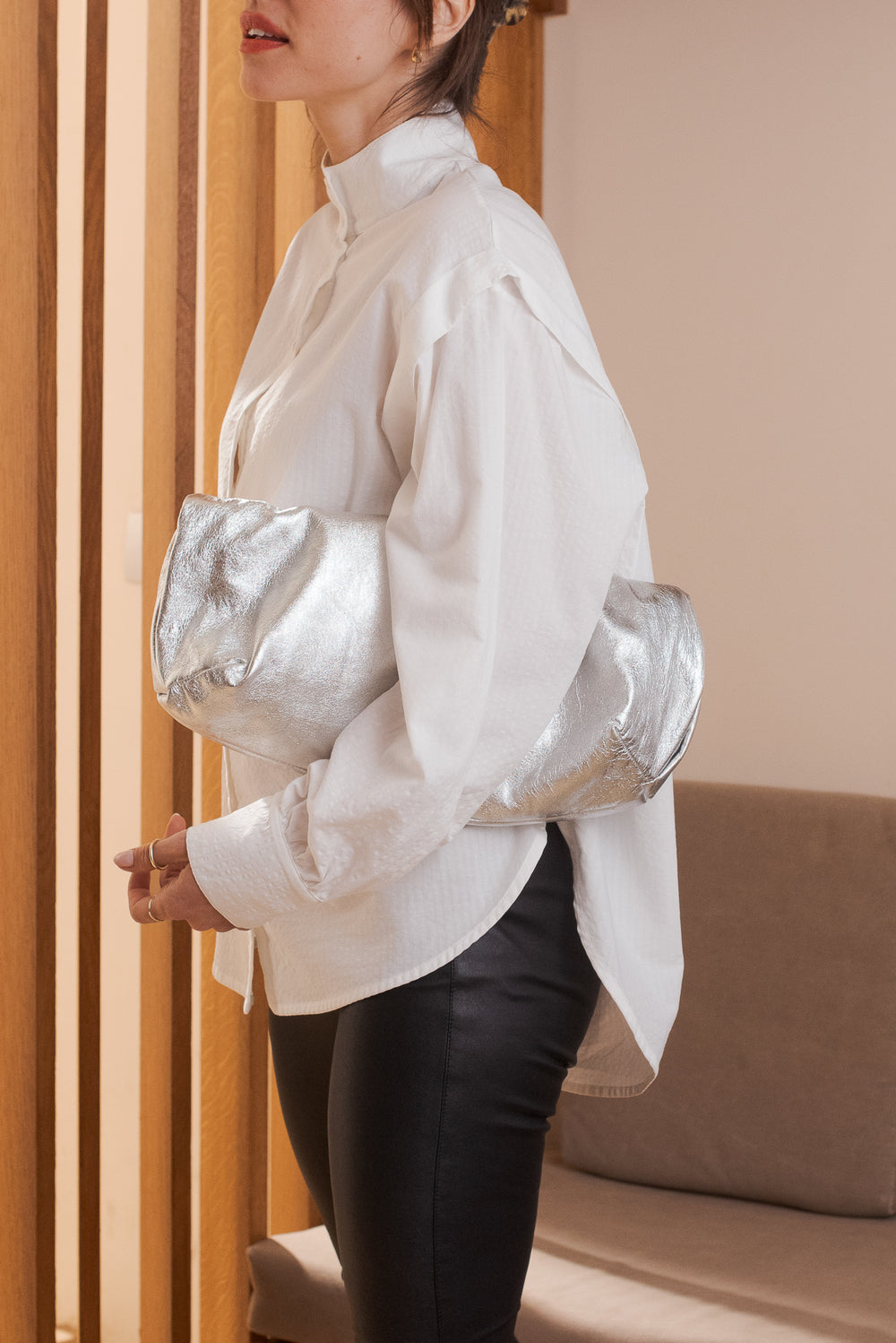 Vue de profil chemise femme blanche Marlot Paris sac argenté sous le bras.