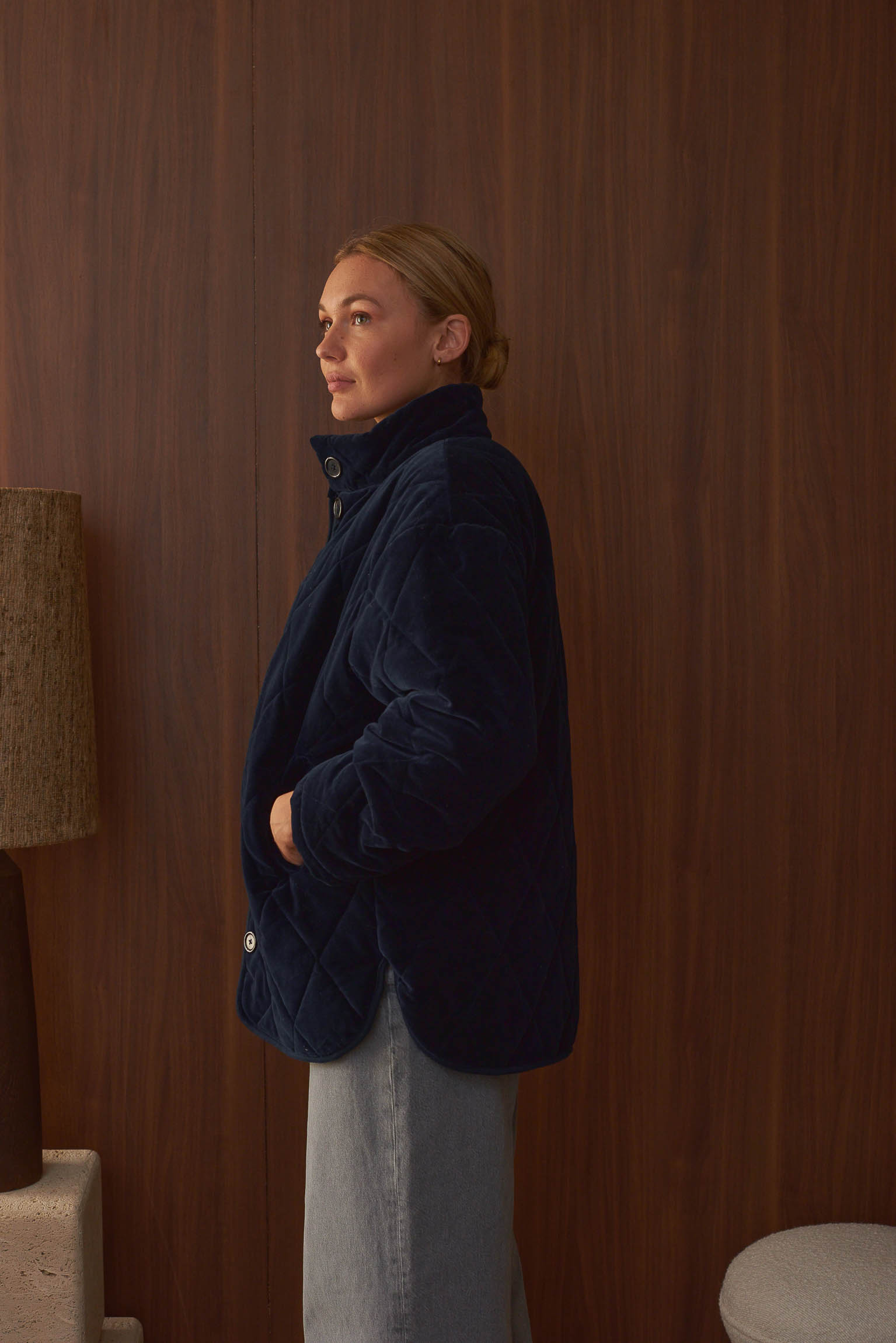 Femme blonde de profil portant manteau velours indigo Marlot Paris.