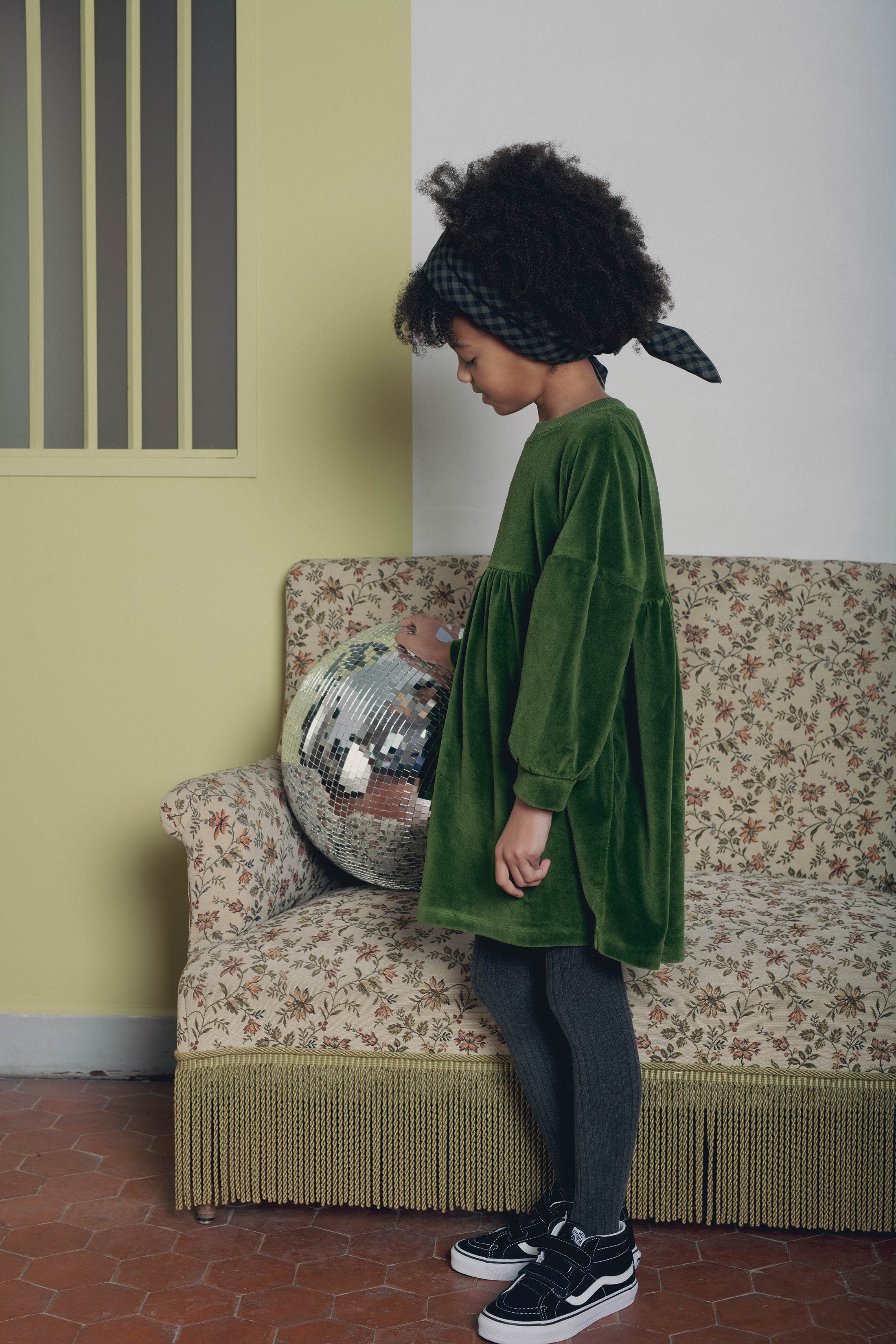 Vue profil robe fille velours vert Marlot Paris canapé et boule disco.
