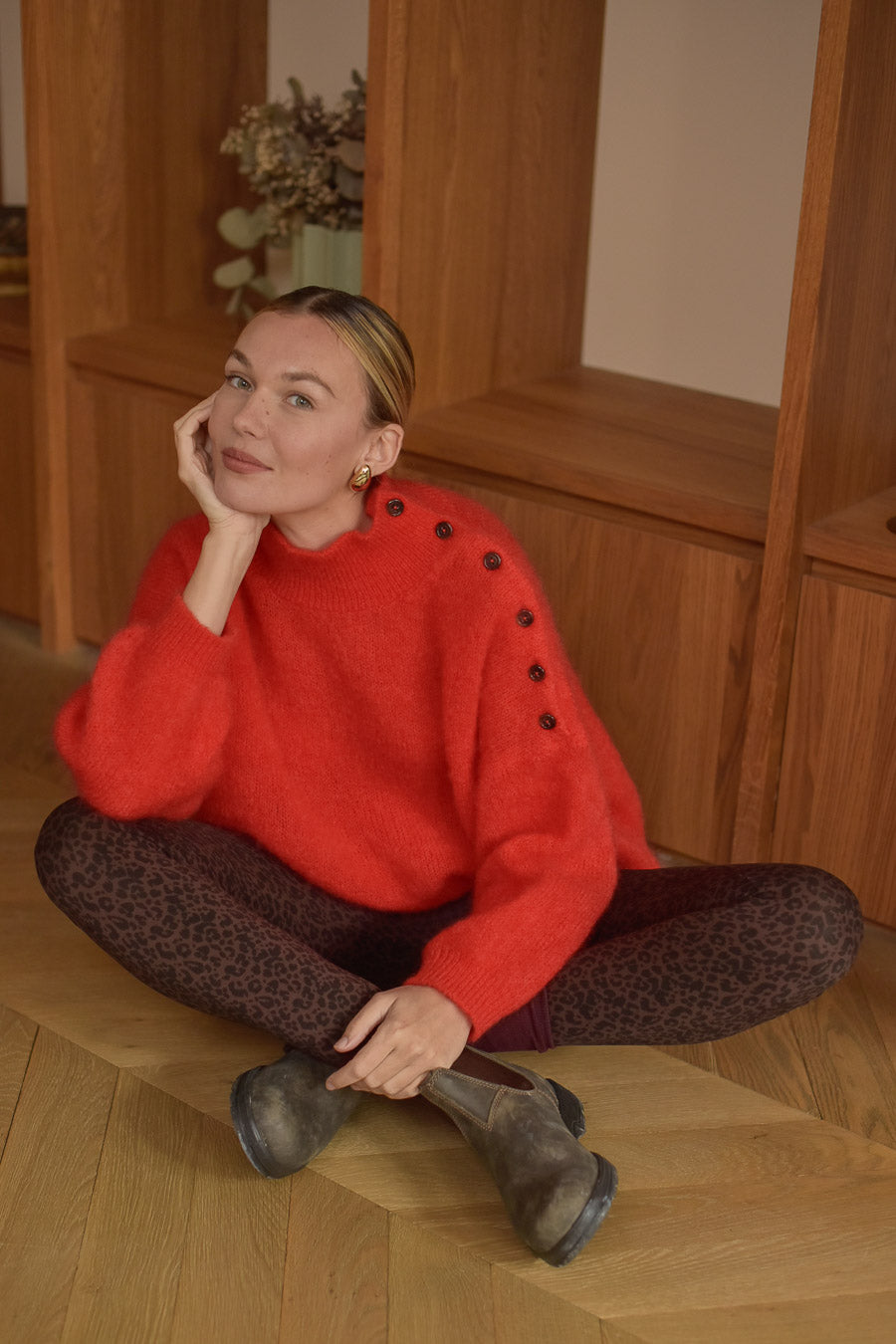 Femme assise tailleur pull rouge mohair et legging léopard Marlot Paris.