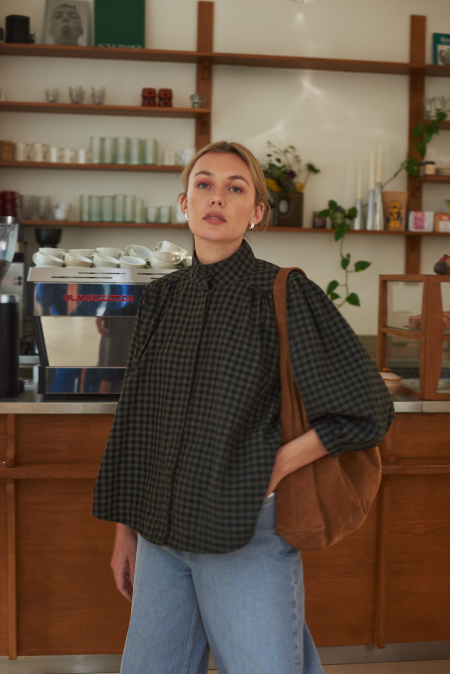Look femme blouse à carreaux kaki et bleu marine devant comptoir café marlot paris.