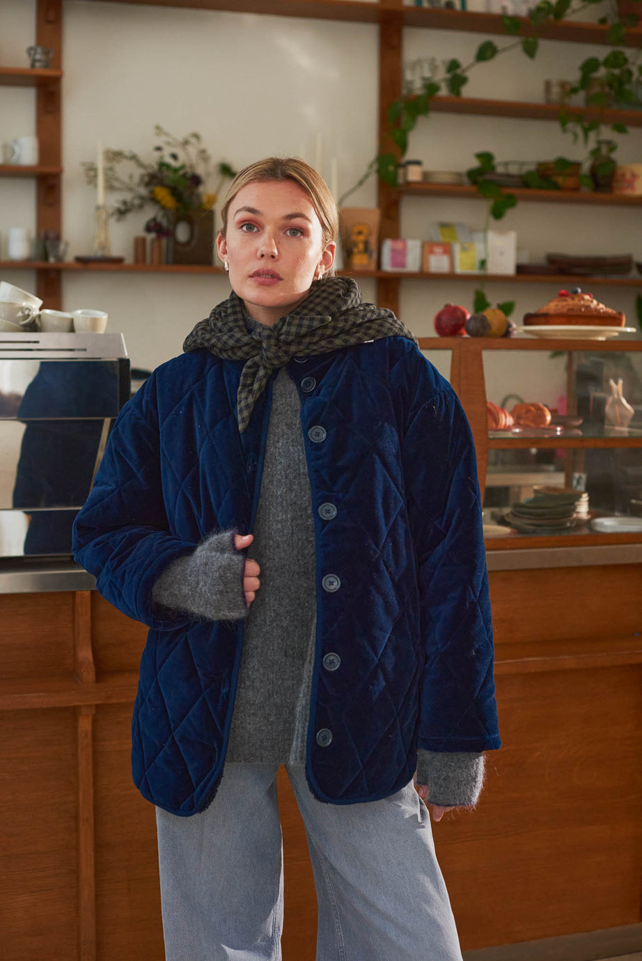Look femme dans café manteau velours bleu et foulard vichy kaki Marlot Paris.